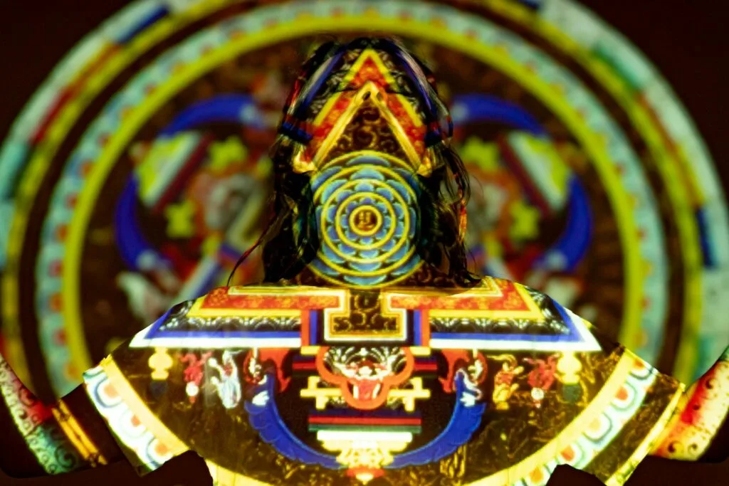 Vibrant projection on woman depicting mystical patterns and spiritual symbols.
